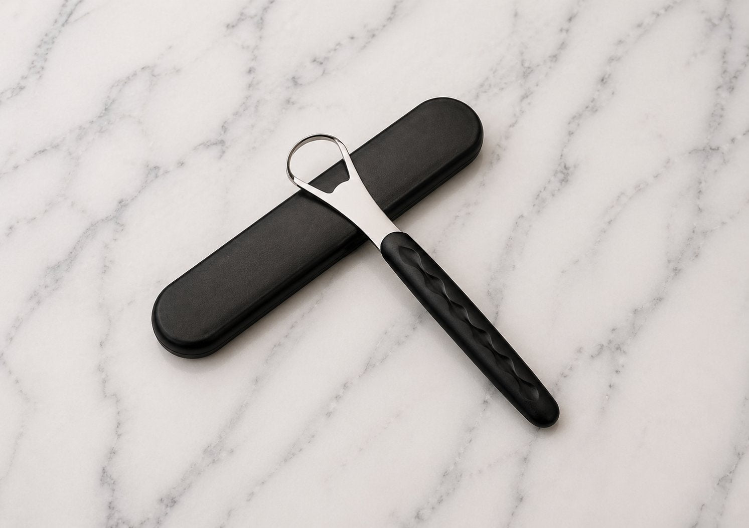Snoshax black tongue scraper with case laid on marble surface premium lifestyle shot