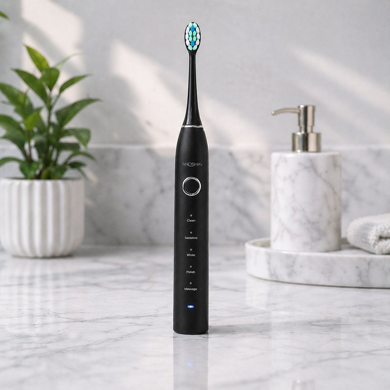 Snosha N2 black electric toothbrush on marble counter with plant and soap dispenser