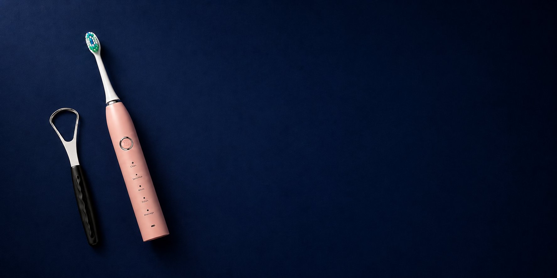 Snosha N2 pink electric toothbrush and Snoshax tongue scraper on dark navy background hero shot